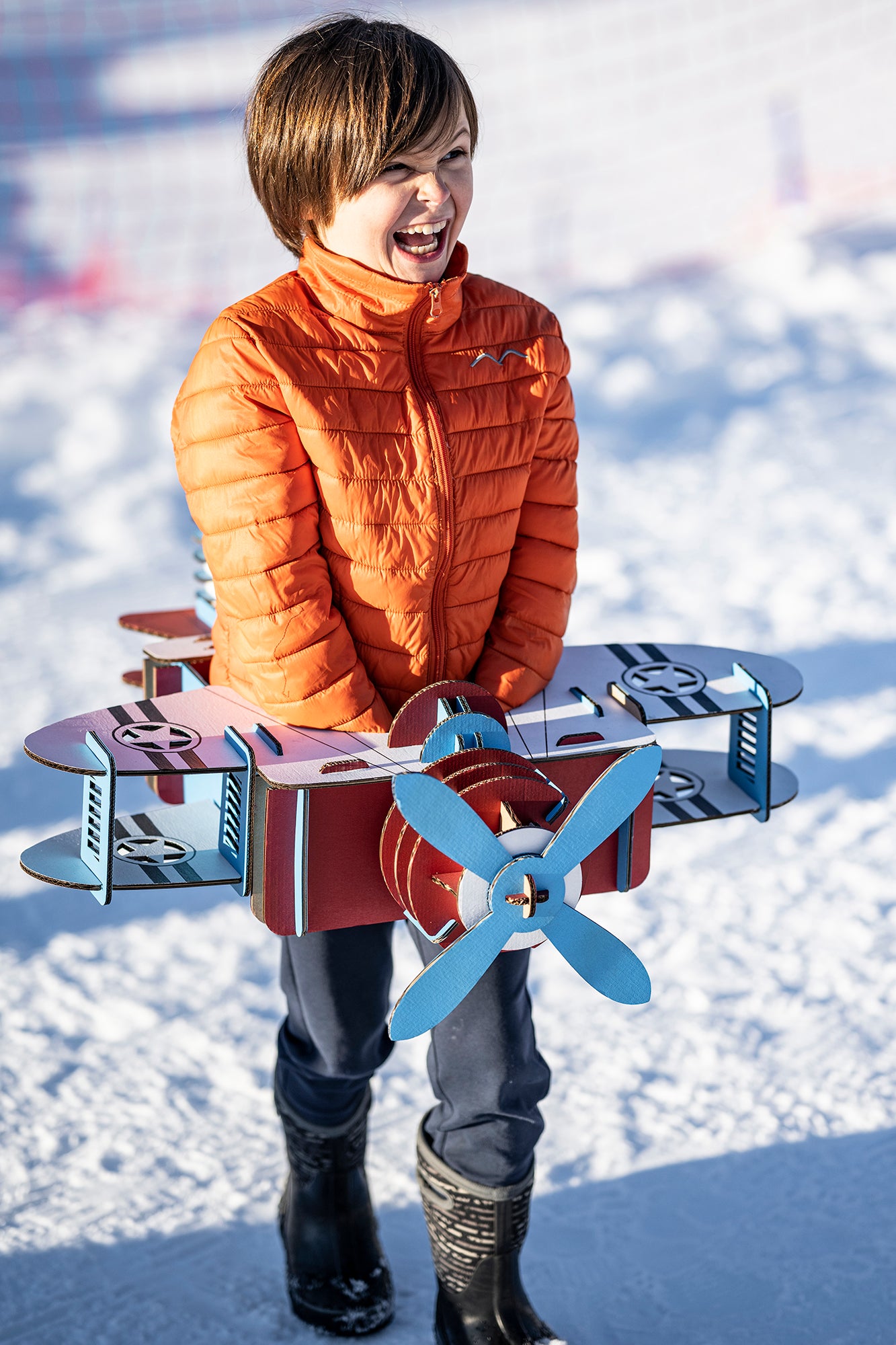 Un enfant en déguisement d'avion en carton recyclé bleu blanc et rouge dans la neige