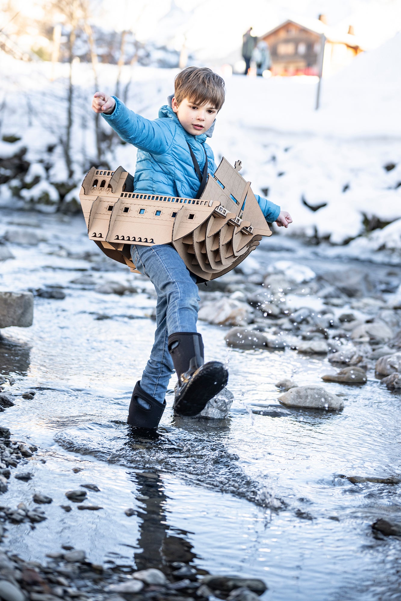 Un enfant qui s'amuse les pieds dans l'eau et en déguisement de bateau pirate en carton recyclé