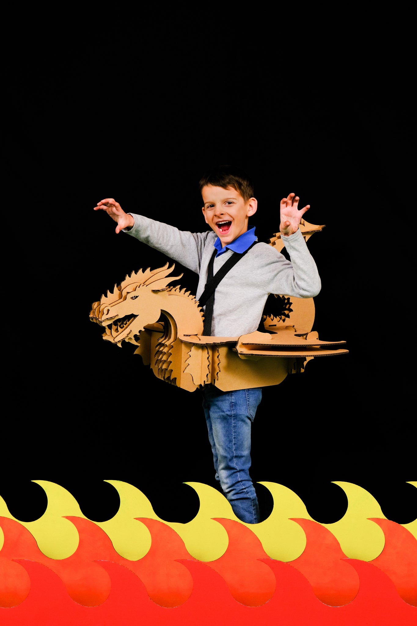 Un enfant dans un déguisement de dragon en carton recyclé au dessus de flamme de couleur en carton, à construire, décorer, peindre et colorier soi même