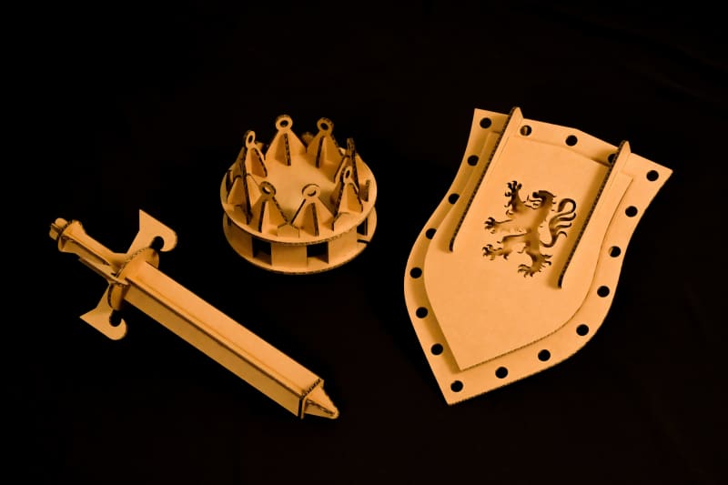 Une épée, un bouclier et une couronne de chevalier roi en carton recyclé pour déguisement, à assembler, décorer, peindre et colorier soi-même sur fond noir